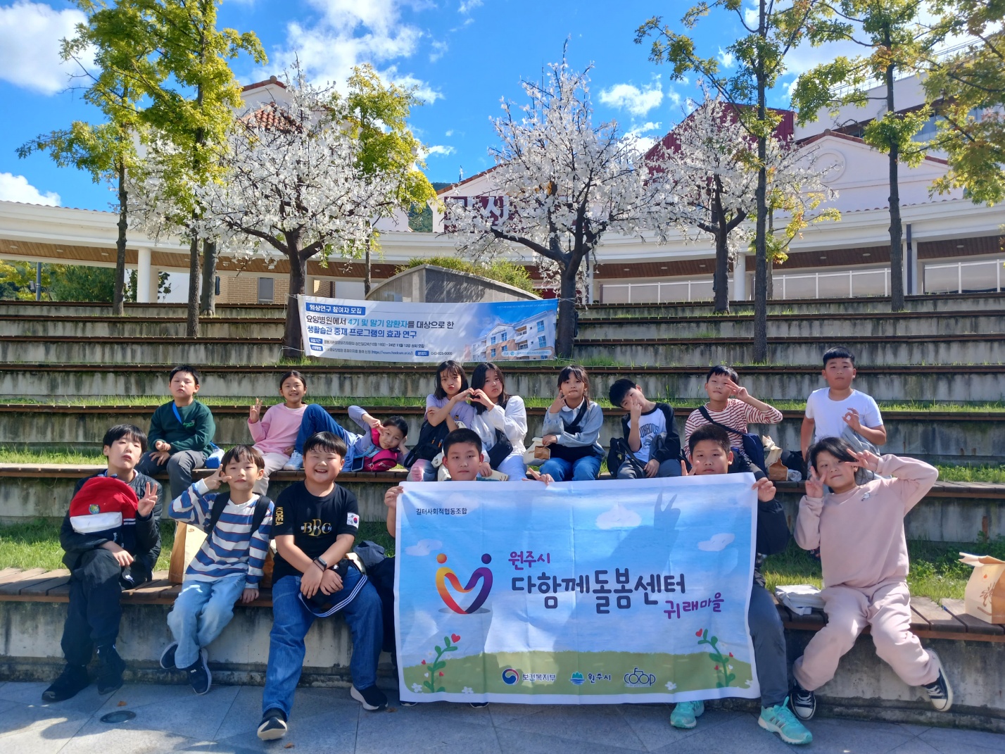 아이들이 다함께돌봄센터 귀래마을 플랜카드를 들고 찍은 단체사진